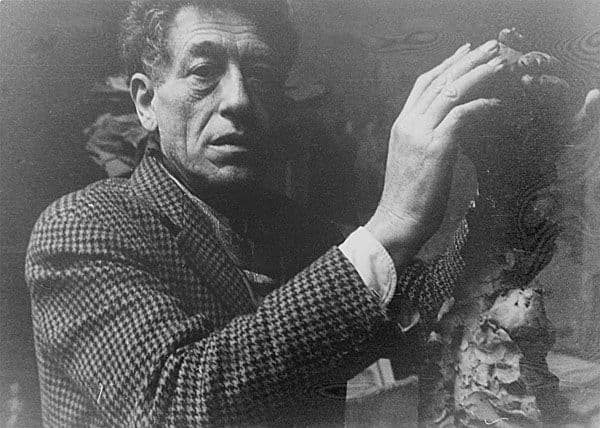 Black and white portrait photograph of a man touching a sculpture