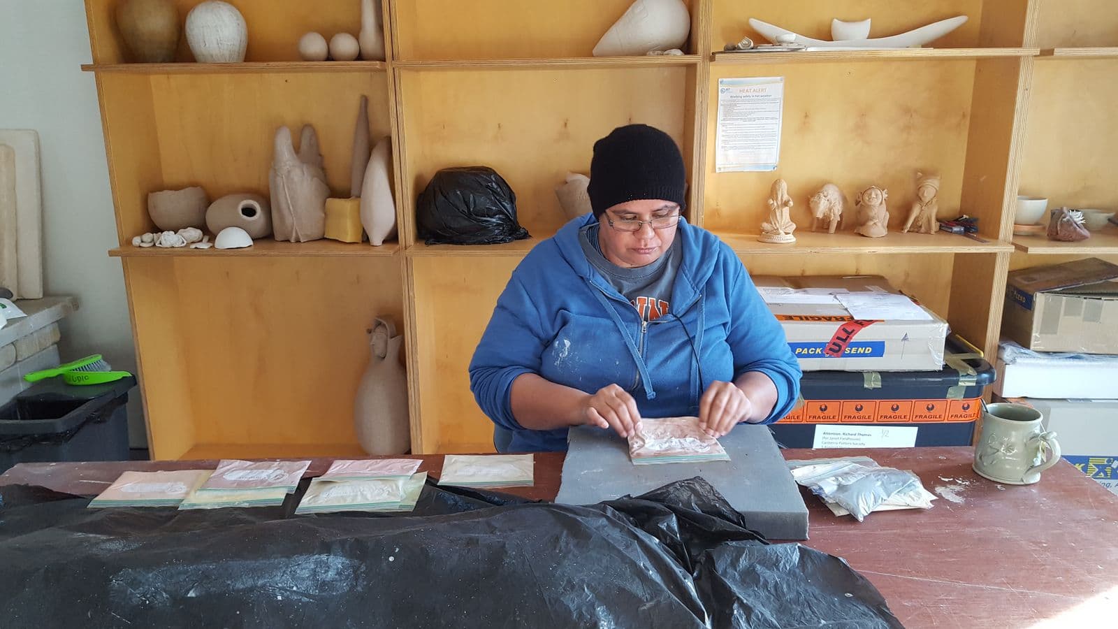 Photograph of Janet Fieldhouse seated in her studio, working on her ceramic pieces