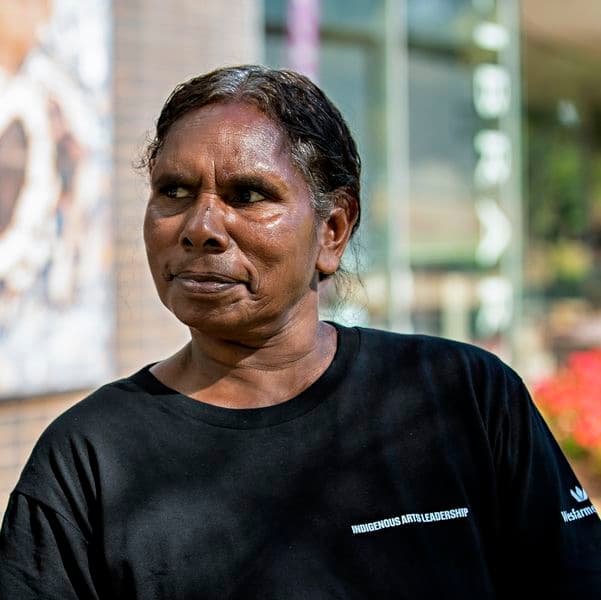 Photographic portrait of a woman standing in front of a colourful artwork