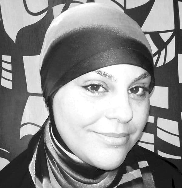 Portrait headshot of a female wearing a head scarf, in front of a patterned background