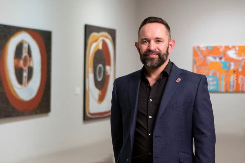 Portrait of a man standing in front of artworks in an Art Gallery
