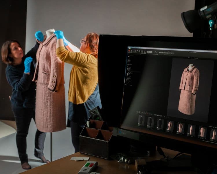 Photograph of pink Chanel suit being fixed by conservators and photographed