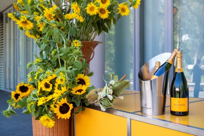 A vase of sunflowers and a bottle of champagne are next to each other on a table