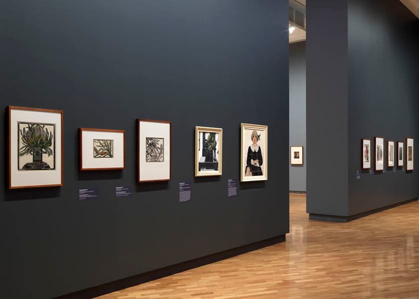 A dark grey wall with small works of art on it