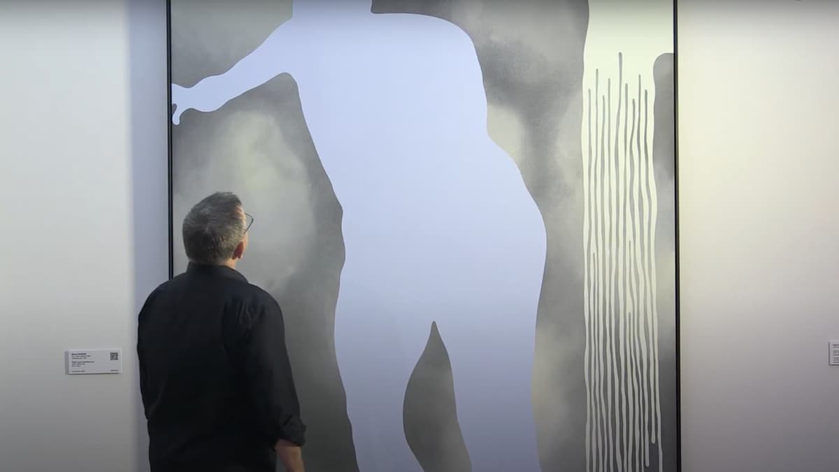 A video still of a man looking at an artwork in a gallery space