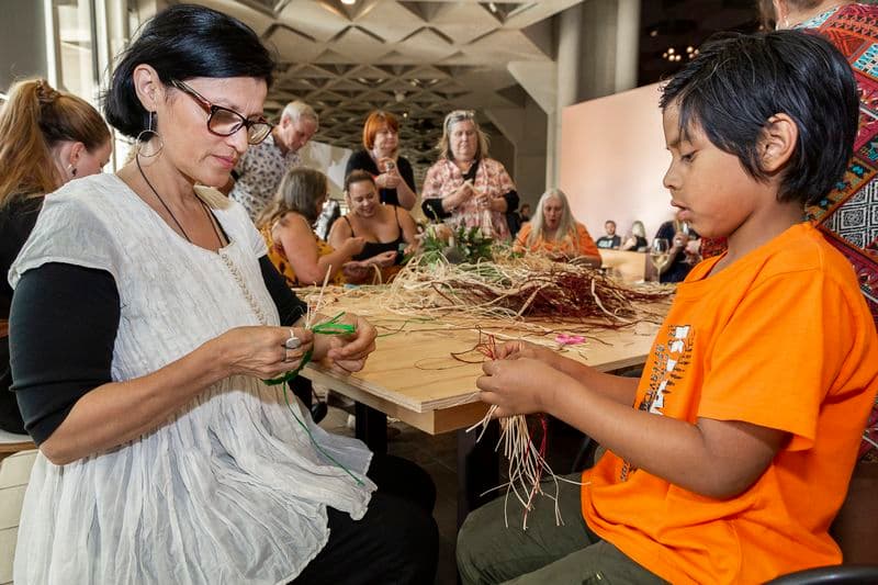 Photograph of family sitting and weaving materials in the gallery
