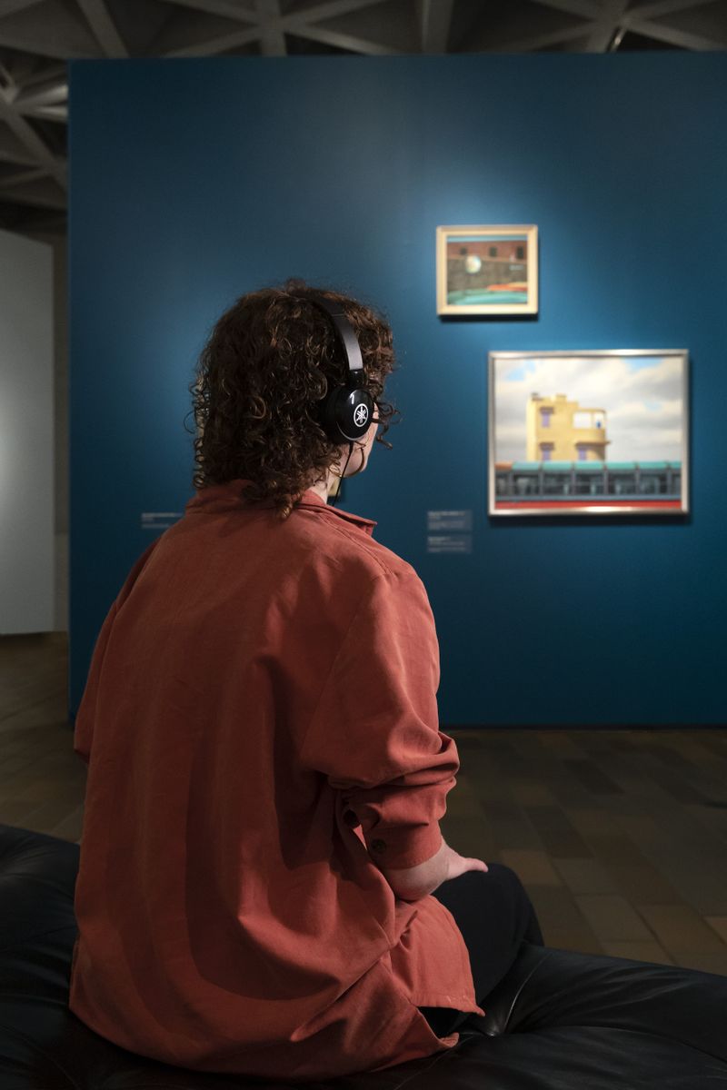 A photo of a woman sitting down listening to an audio tour.