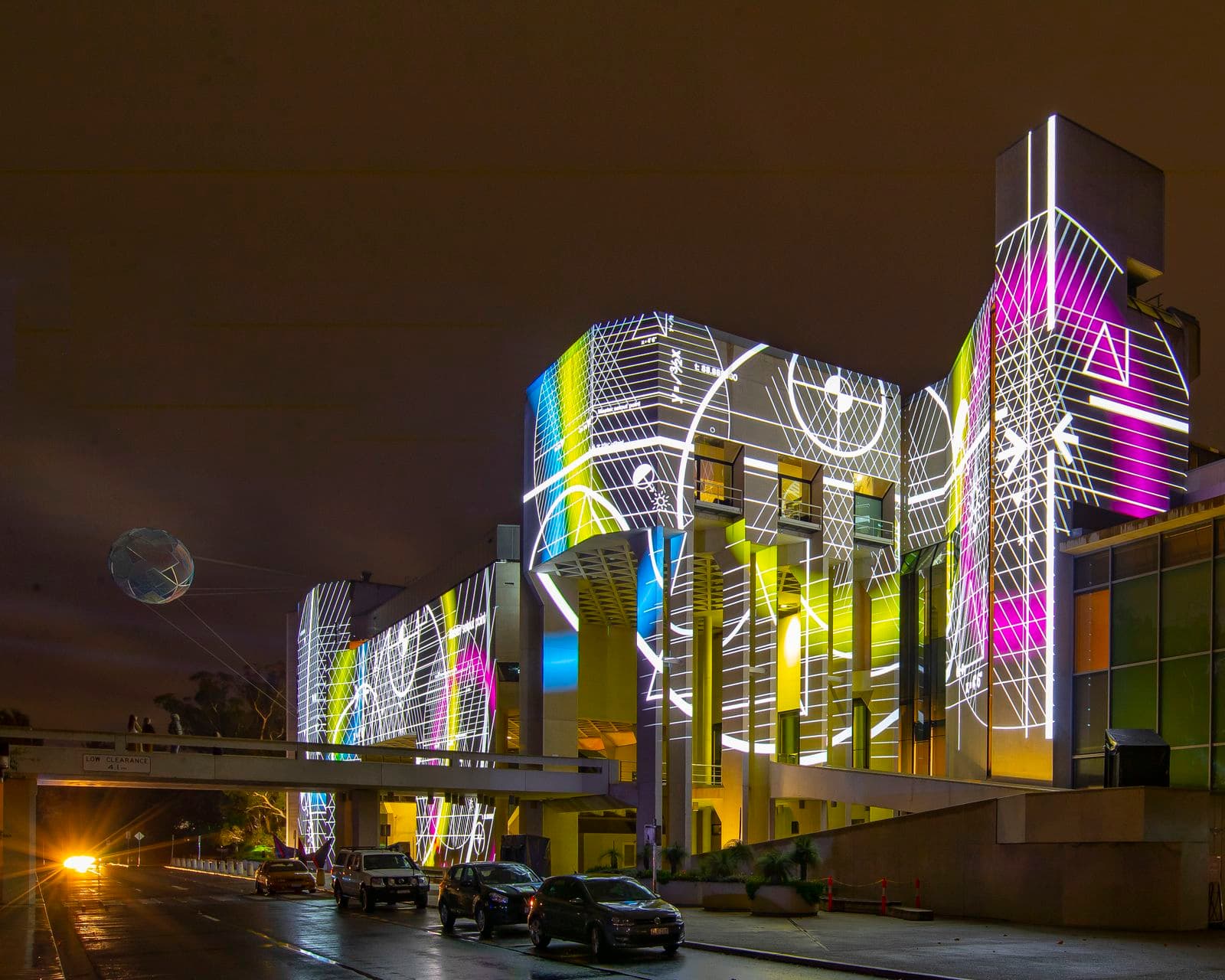 Colourful geometric work of art created in light is projected onto the brutalist concrete architecture of the National Gallery