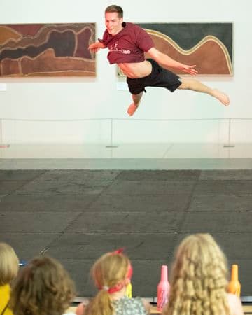 Audience of young people watching a young male dancer leaping in the air