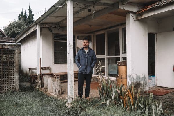 A man stands in front of a house