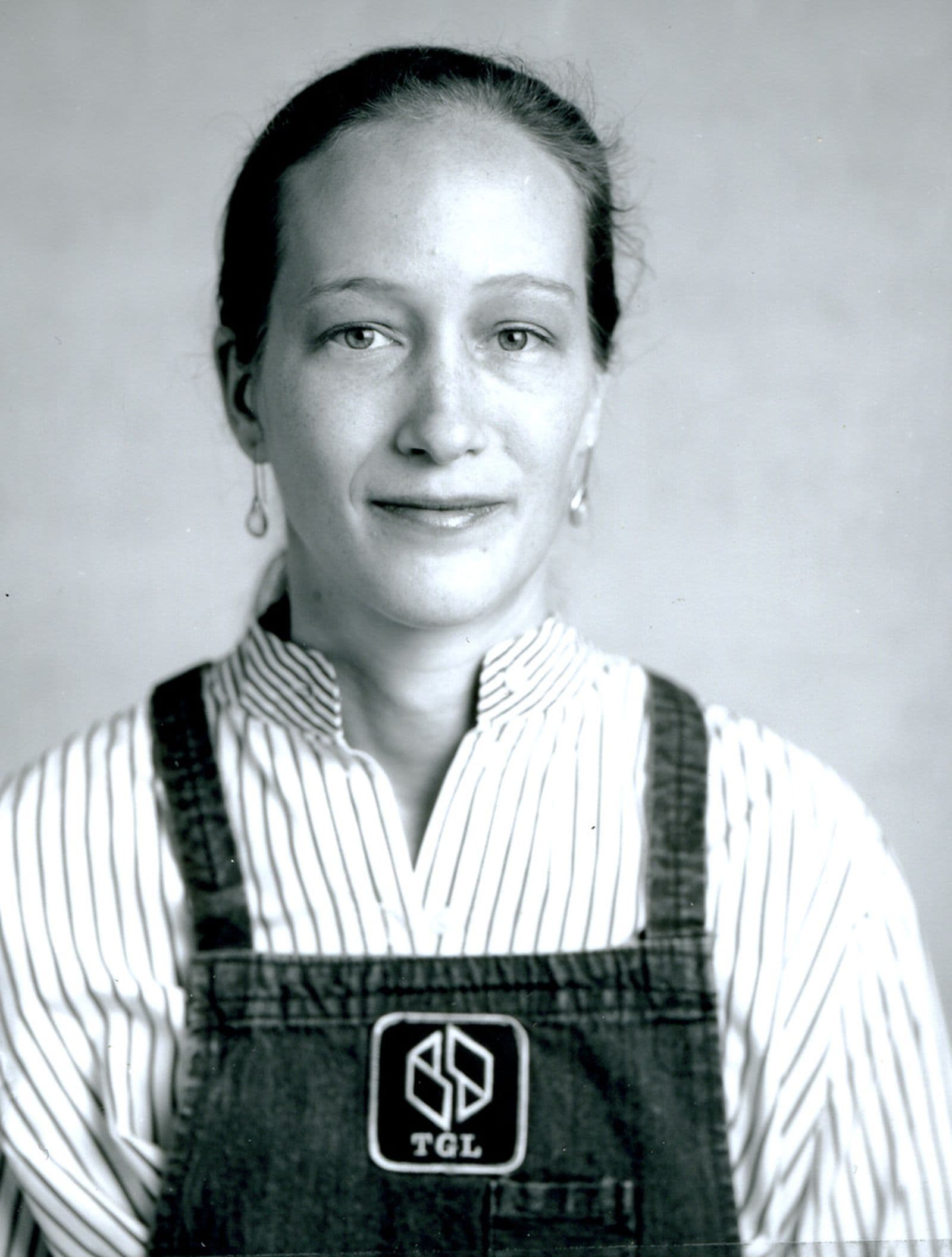 A black and white photograph of a woman wearing overalls