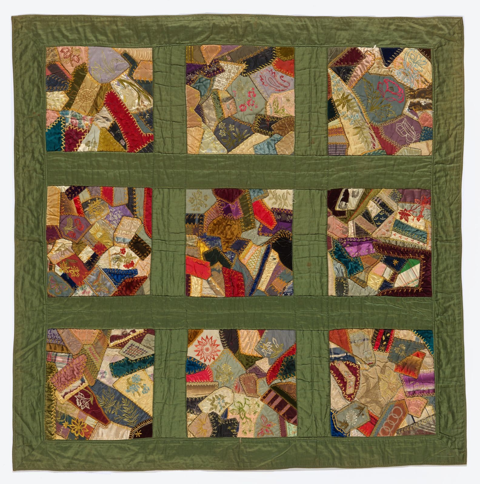 Quilt consisting of nine squares containing patchwork, surrounded by a green border.