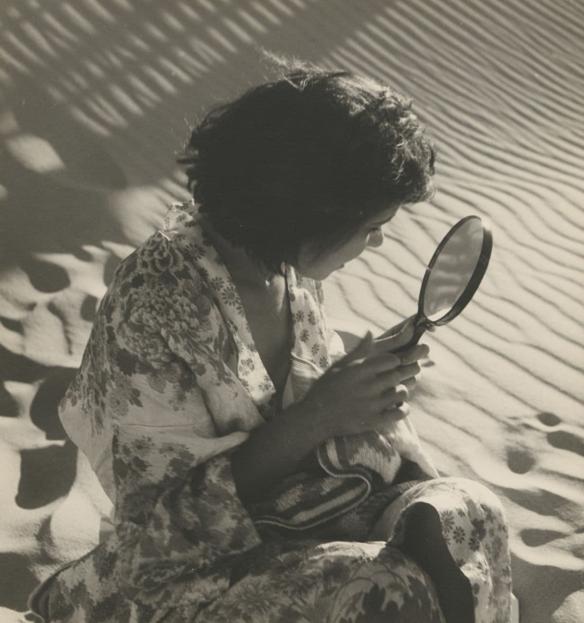 Photo of a woman's side profile as she looks into a hand mirror