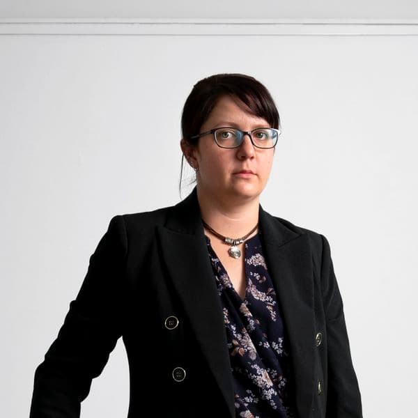 Photographic portrait of a woman standing against a white background.