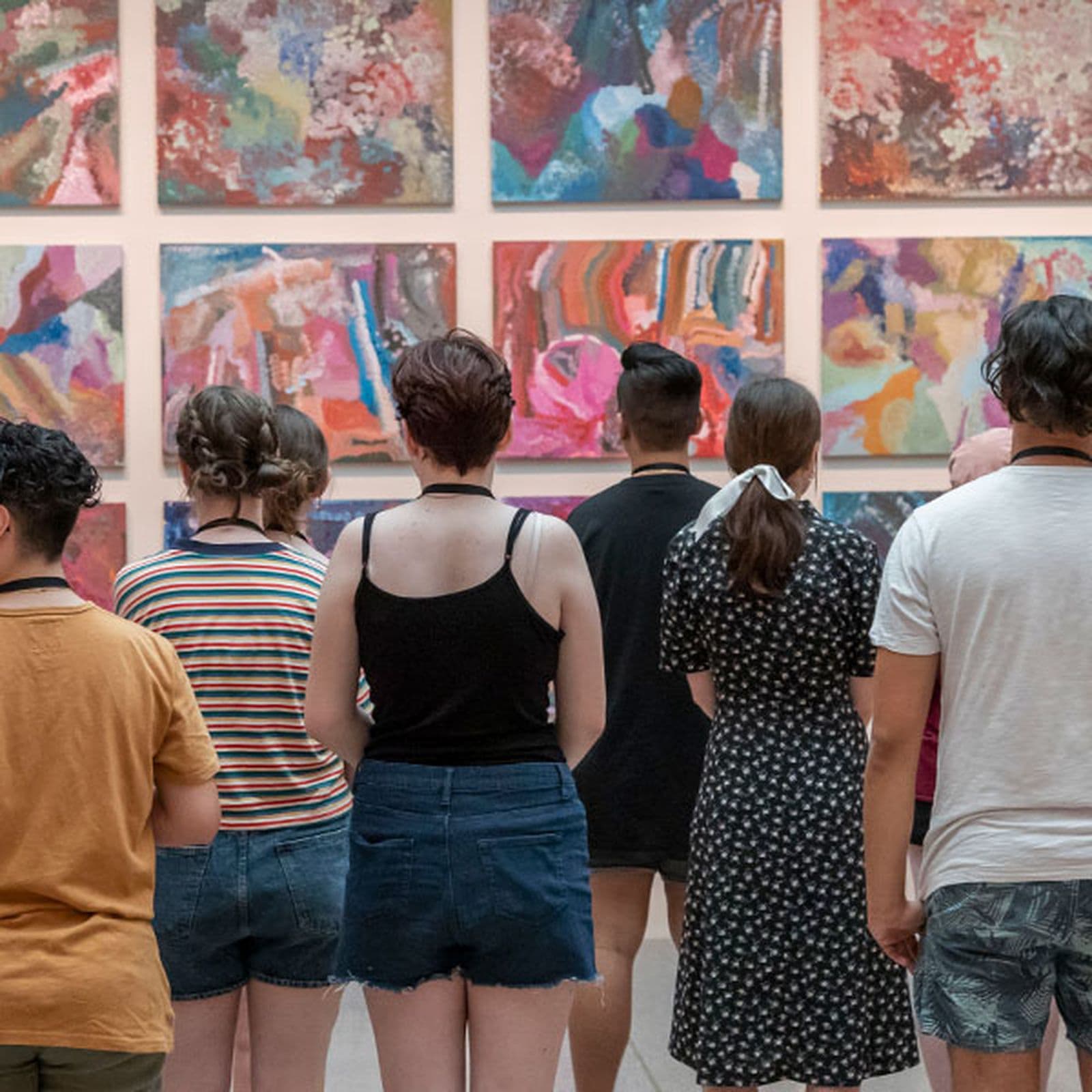 Back view of a group of Secondary school students looking at an Indigenous work of art on a wall
