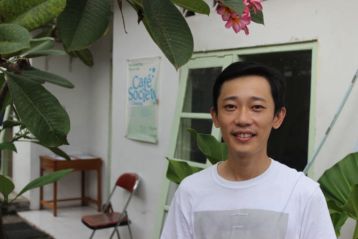A man in a white t-shirt smiles at the camera