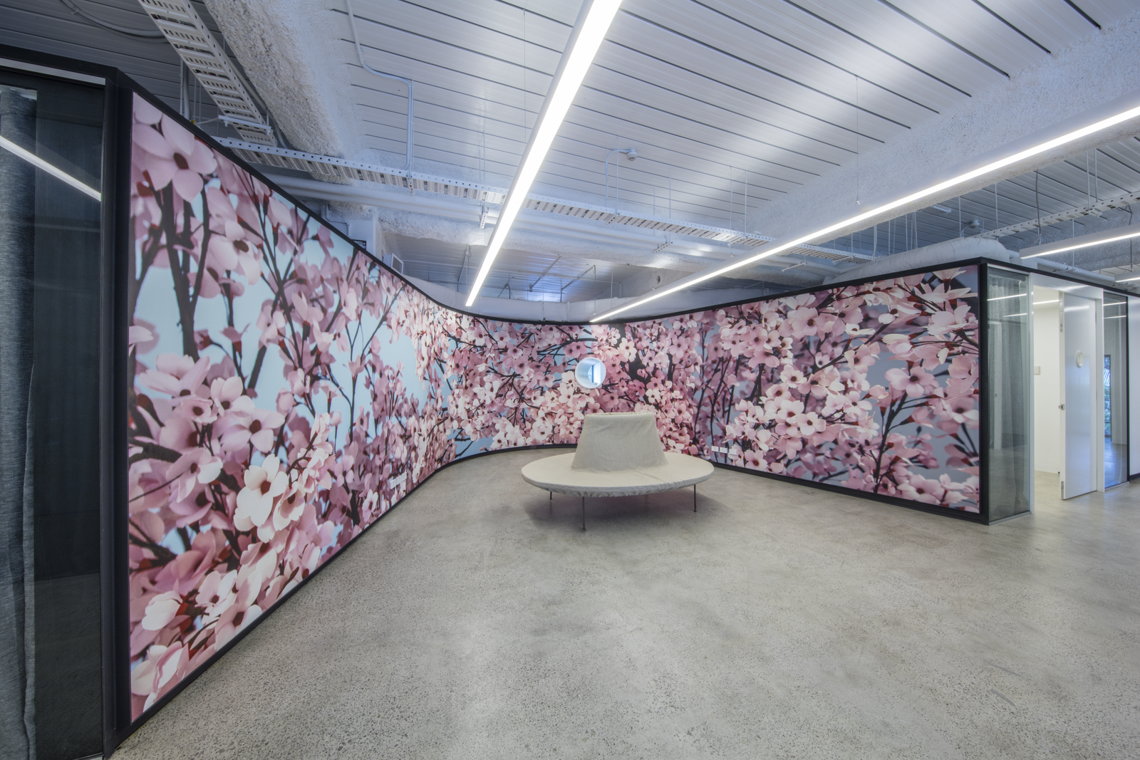 Photograph Sussan Group office with curved wall with cherry blossom wallpaper and a white Pouf