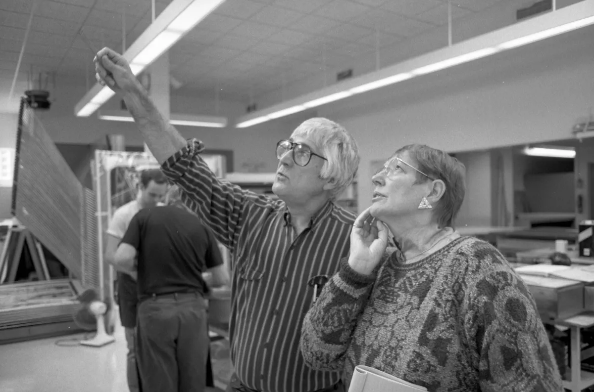 Black and white photo of Kenneth Tyler and Pat Gilmour looking up at artwork