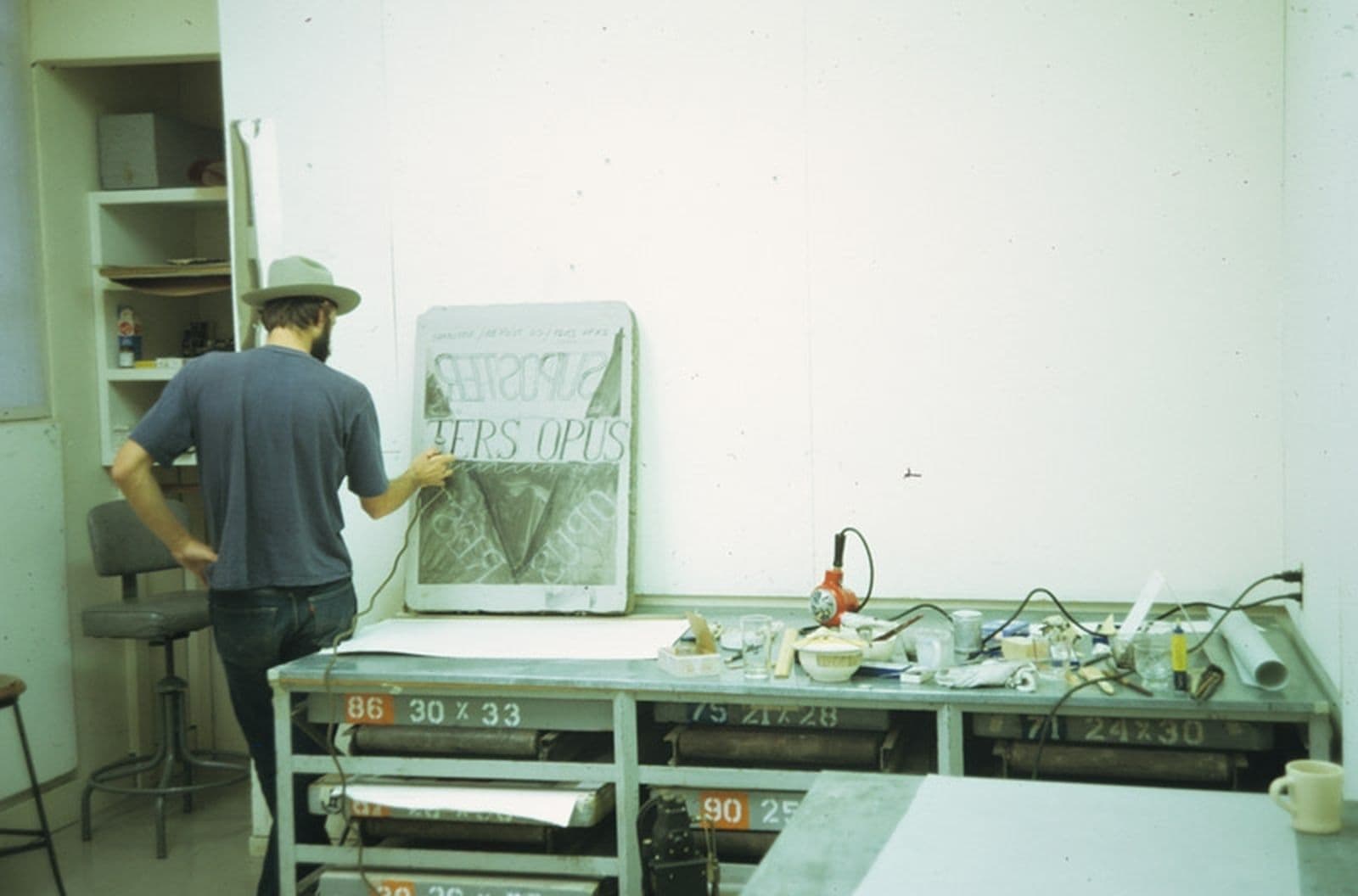 Colour photo of Bruce Nauman drawing on a lithographic stone for his three colour lithograph and screenprint.