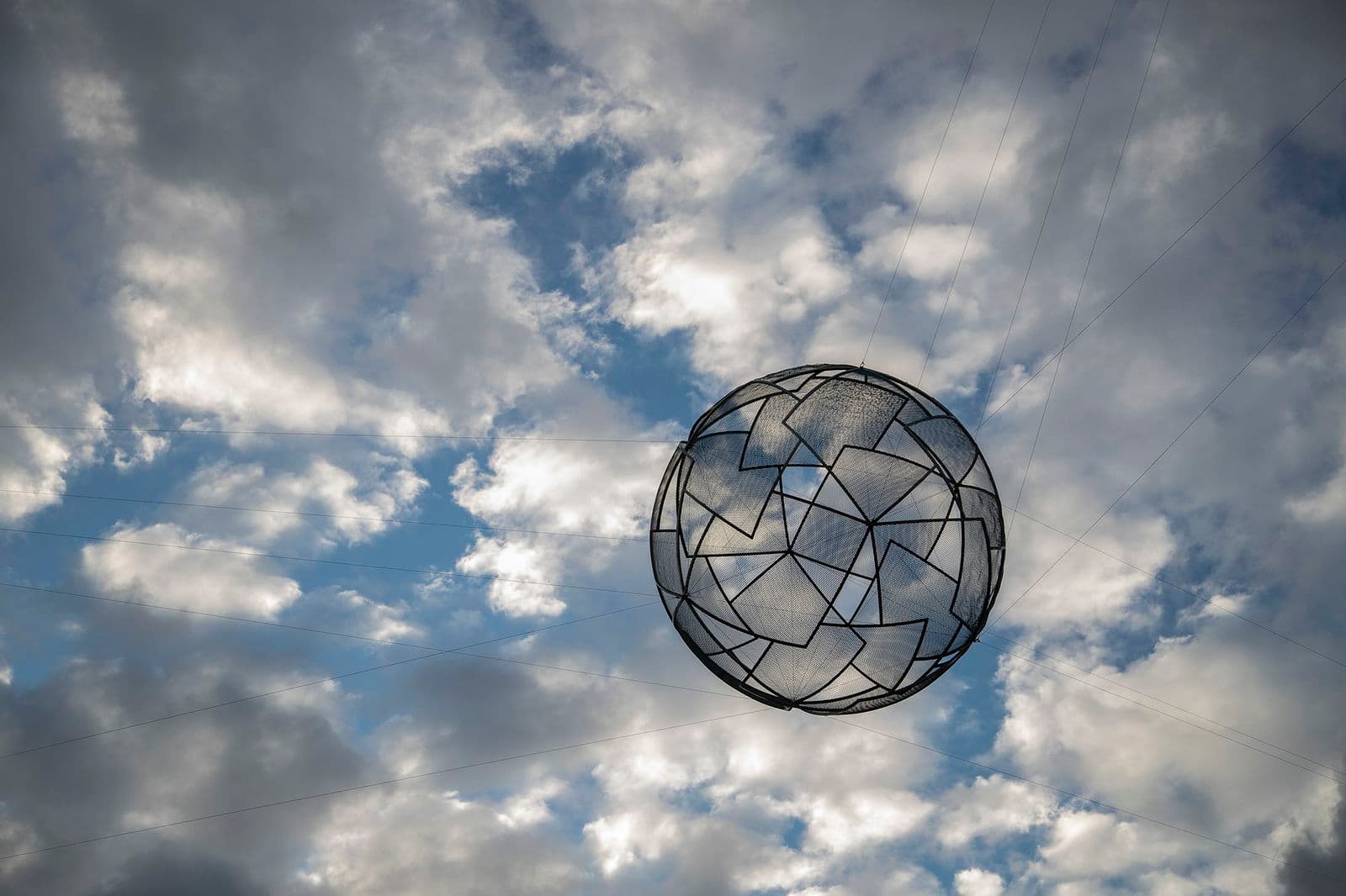A sphere made of interlocking geometric shapes hangs in the sky