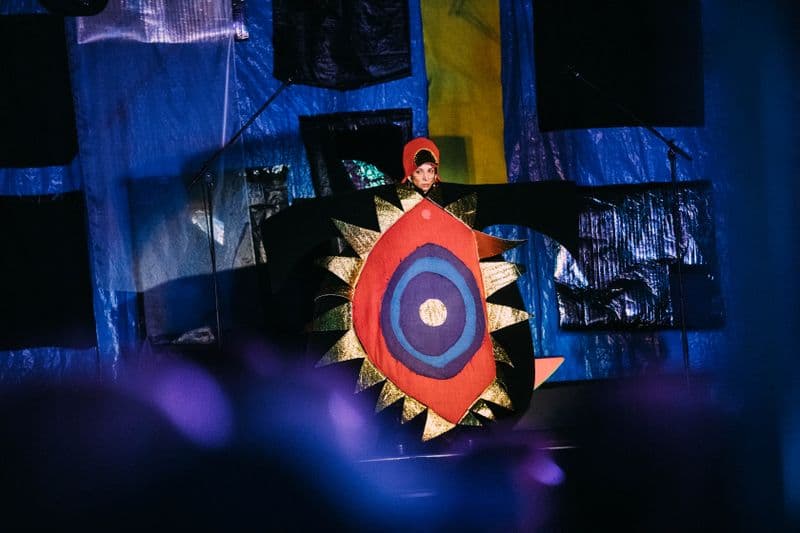 Photo of female performer in large circular costume in red and purple materials
