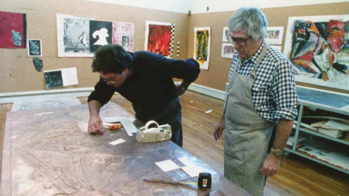 A video still of two men in a studio