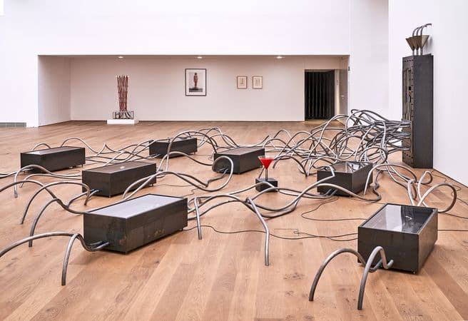 Photograph of brown boxes strewn across a timber floor, connected by silver piping.