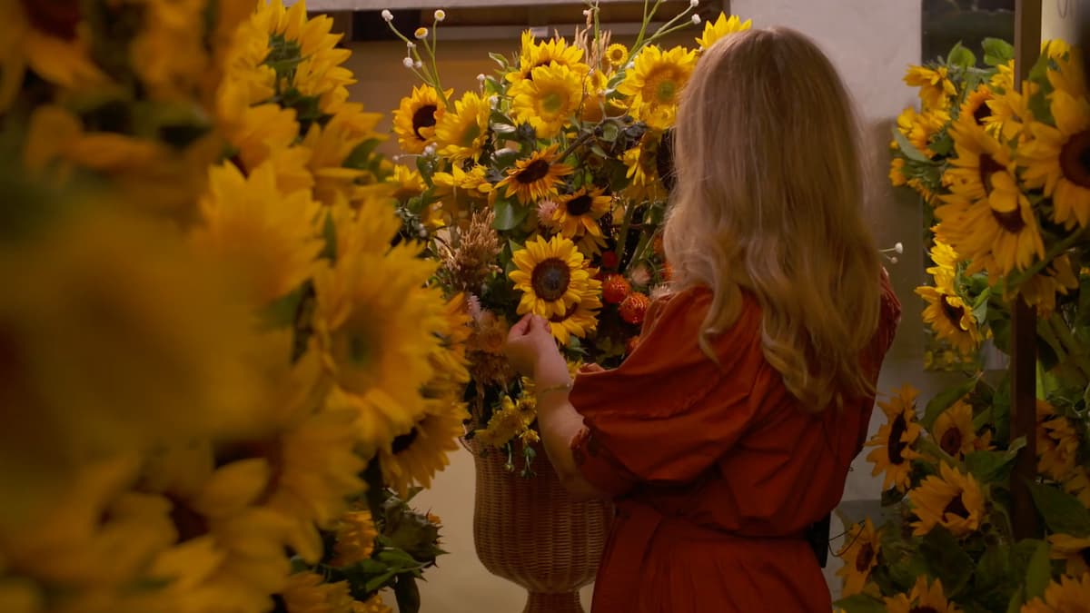 A video still of a woman surrounded by sunflowers