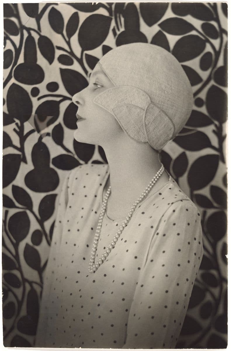 A black and white photograph of a young woman in a cloche hat