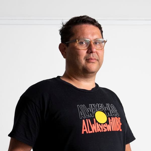 Photographic portrait of a man standing against a white background.
