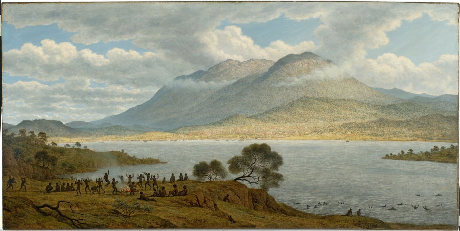 Landscape of large mountain with a body of water at the base, in left foreground a community of indigenous peoples ceremonially dance around a campfire