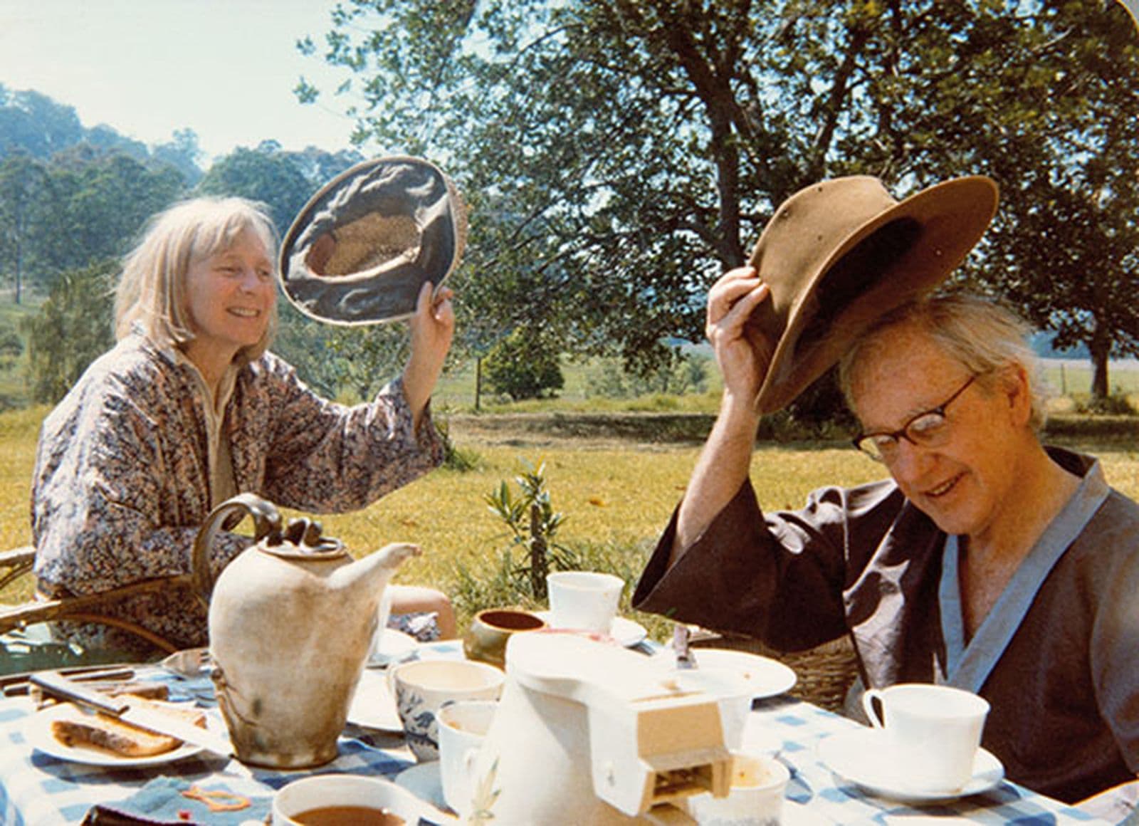 Photograph of two people smiling and waving hats at the picnic