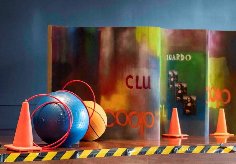 Photograph of an urban, Jeffrey Smart-inspired installation featuring a spray painted wall, hoops, large balls and traffic cones