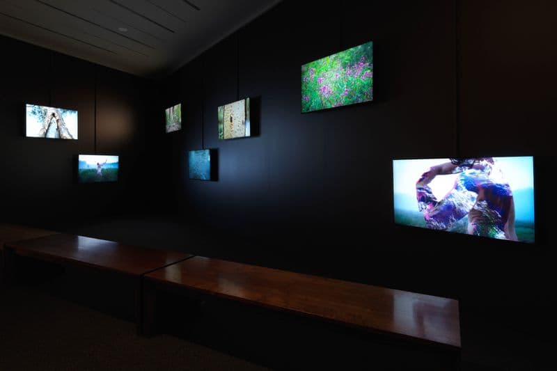 A dark room with multiple screens hung on the wall showing various sections of a film