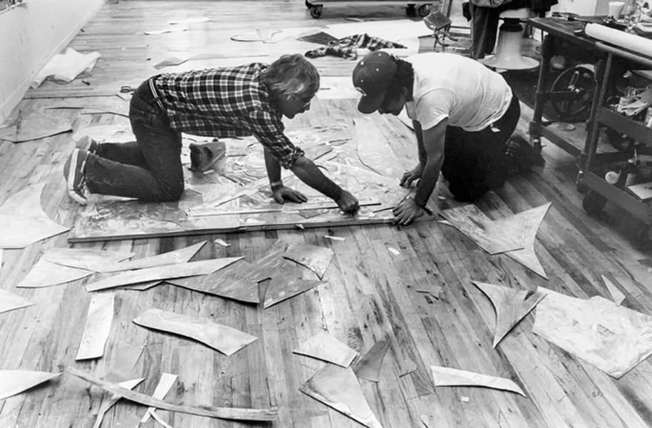Black and white photo of Frank Stella and Kenneth Tyler on the ground assembling magnesium plates for ‘Swan engraving IV’