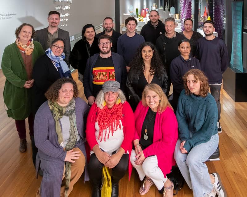 A group of people pose in a group facing the camera to have their photo taken