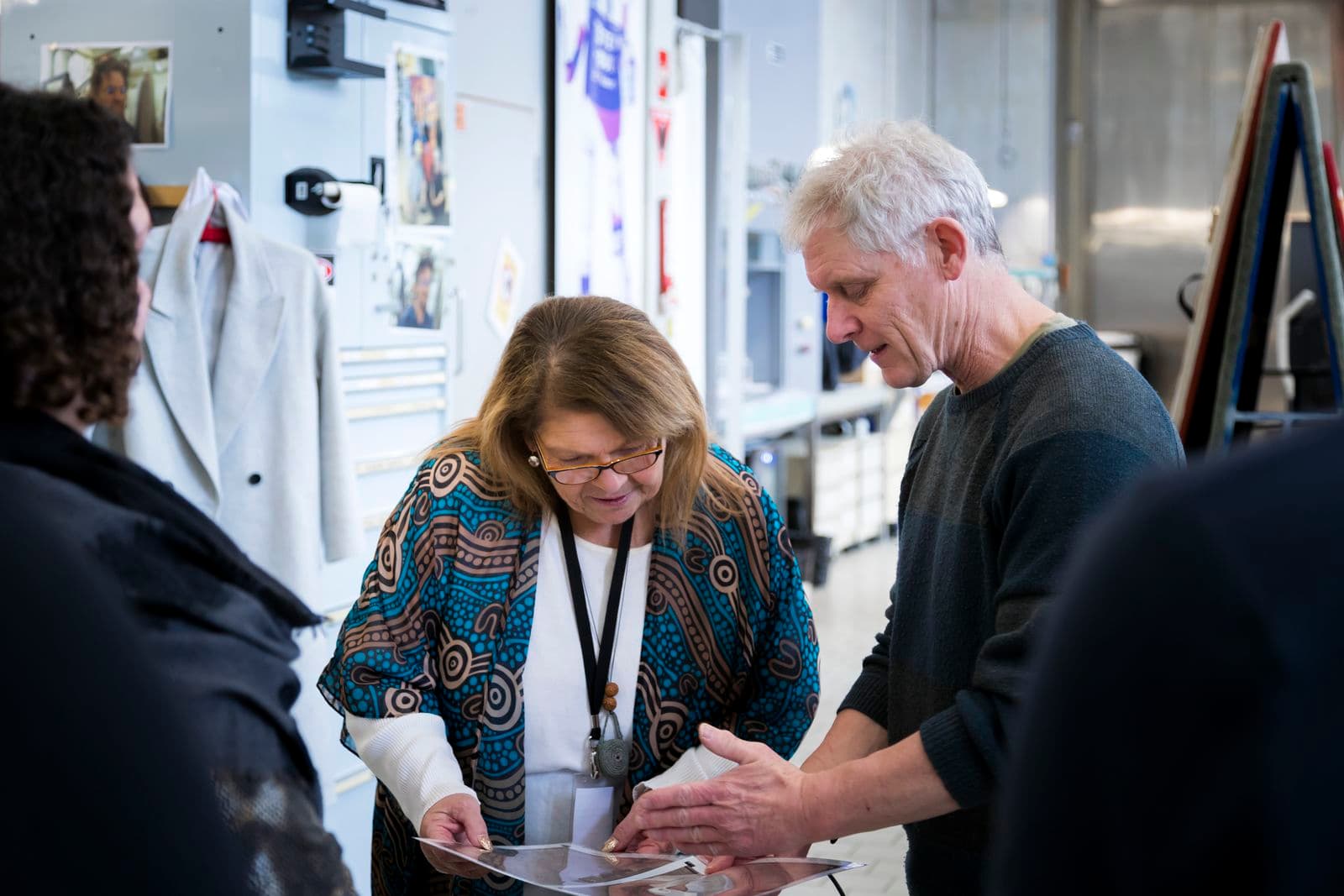 A man is showing a woman images on a piece of paper in an art conservation laboratory