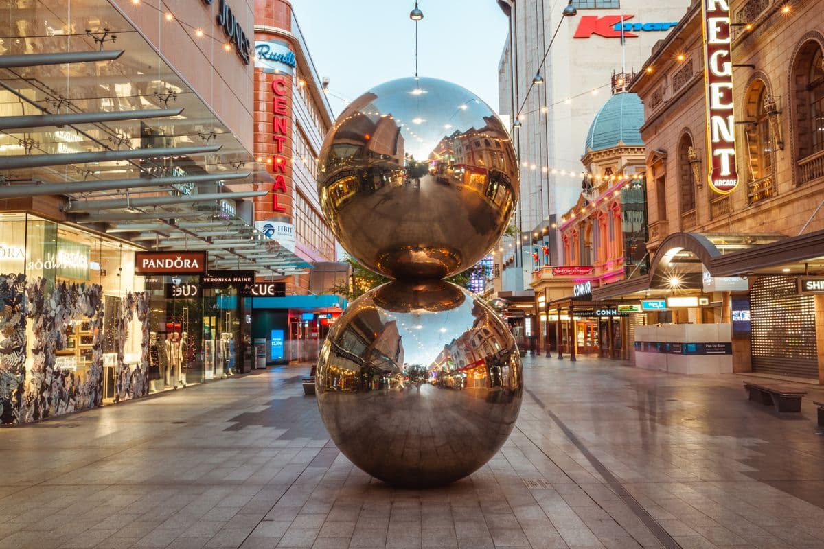 Large sculptural work of two vertically stacked polished steel spheres surrounded by buildings.