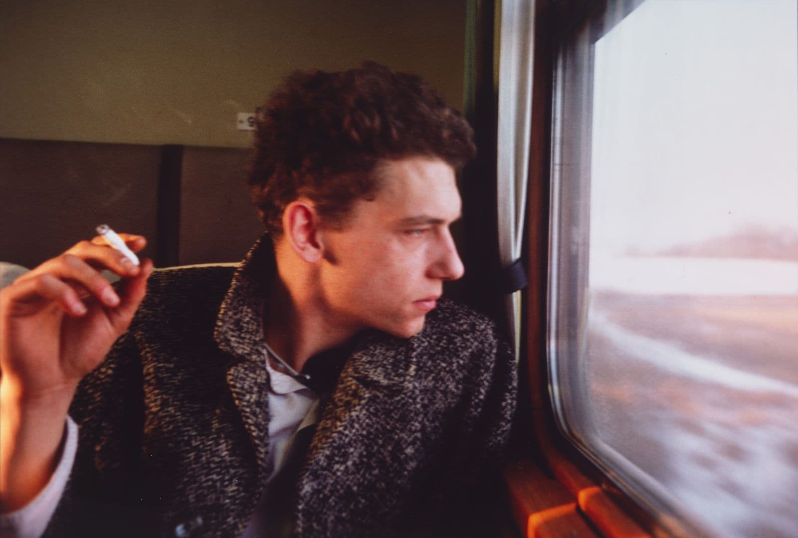Friends of artist Nan Goldin looking out of a window on a train whilst smoking a cigarette.