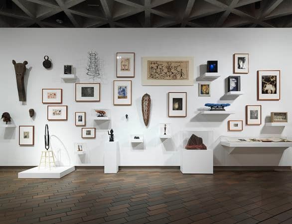 Photograph of a gallery wall featuring a salon hang of surrealist works of art