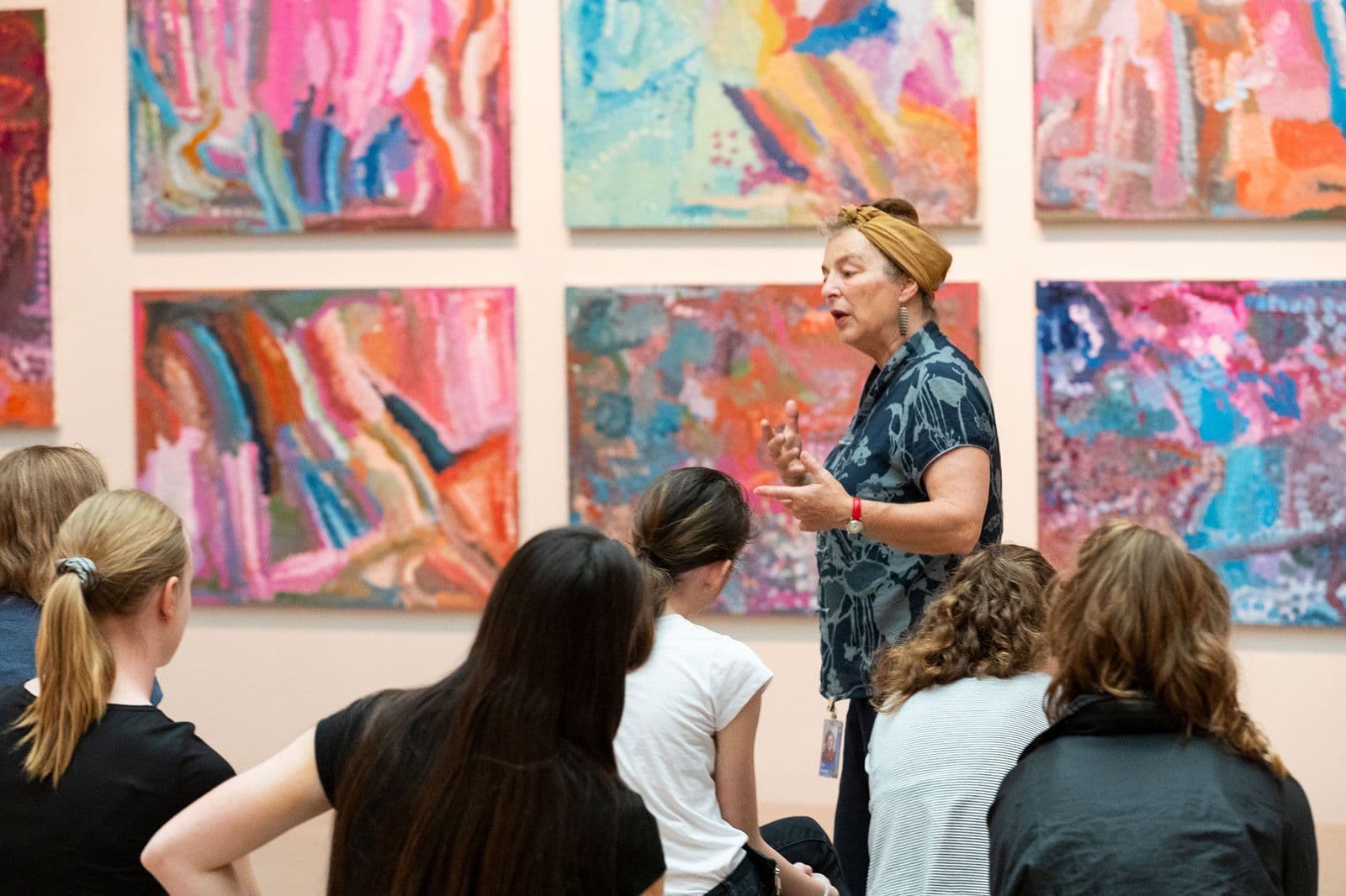 Photograph of speaker gesturing at colourful artwork in front of group