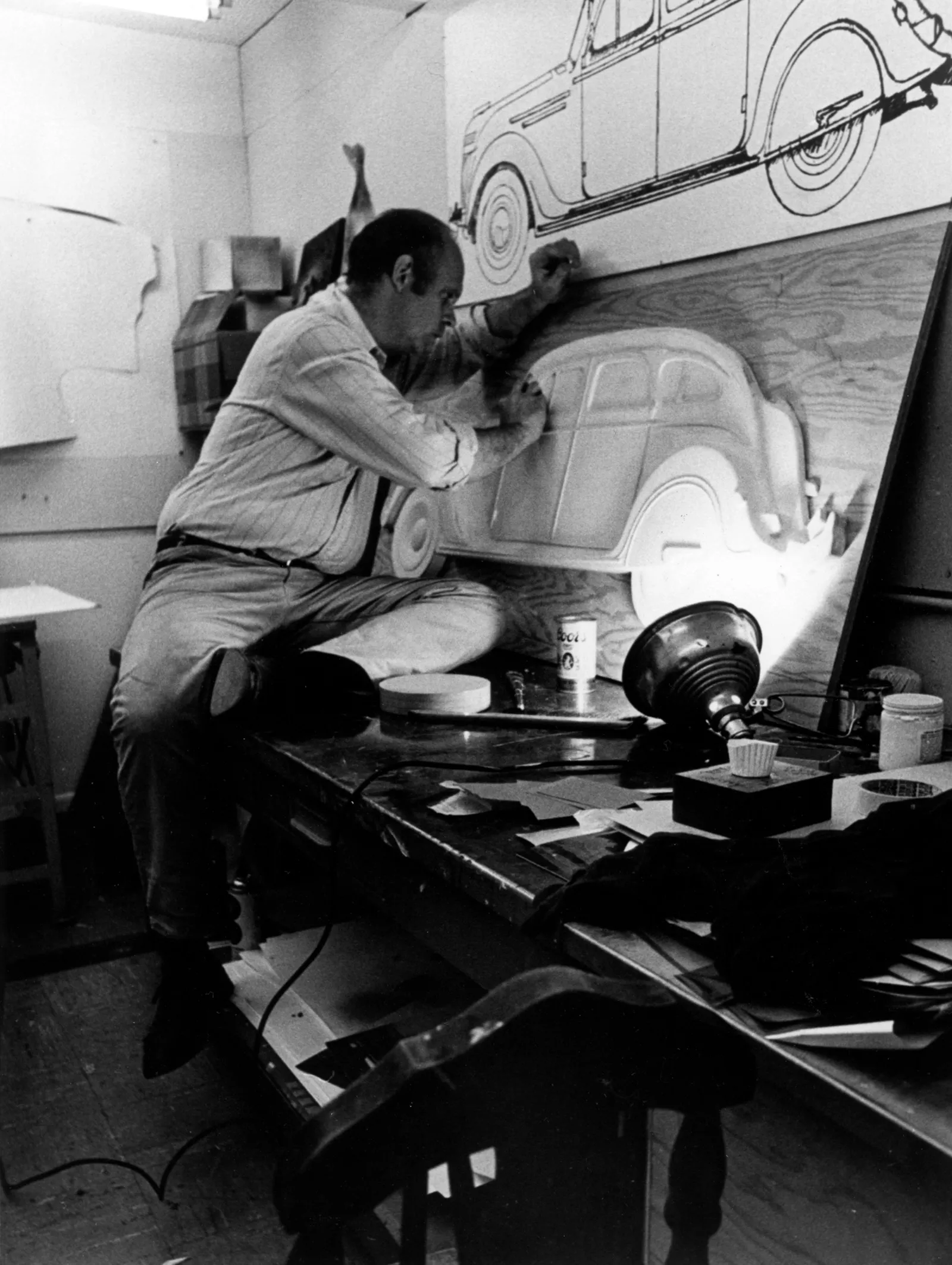 Black and white photograph of Claes Oldenburg working on the original wooden relief