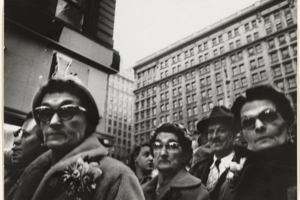 A black and white photo of harried Christmas shoppers looking down at the photographer