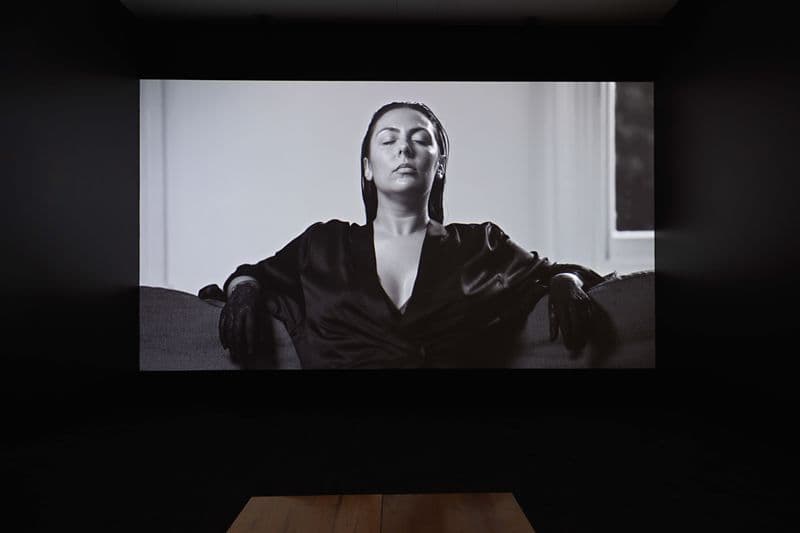An installation view of a screen showing a black and white film