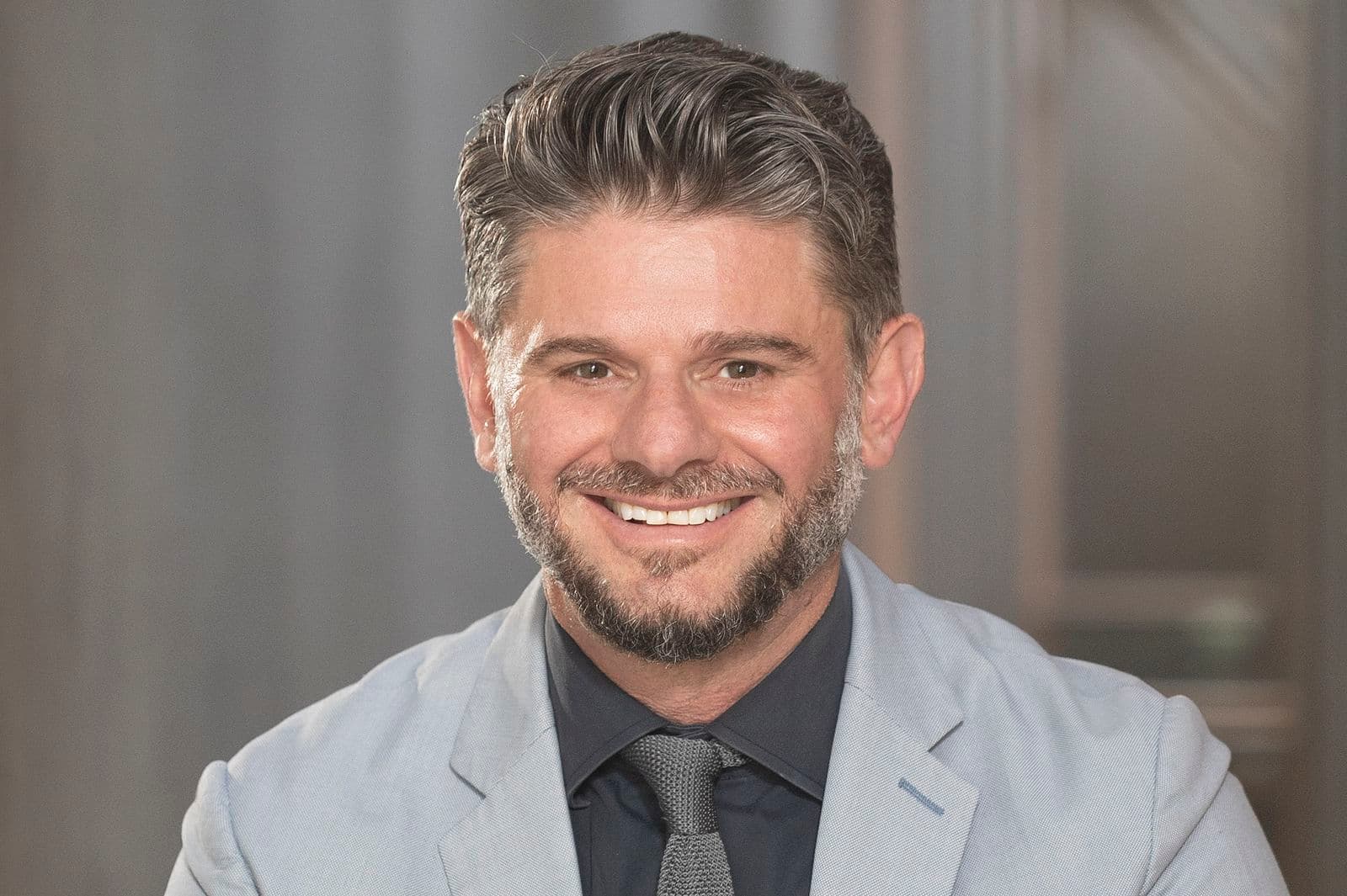 Portrait of a smiling brunette man in a grey suit