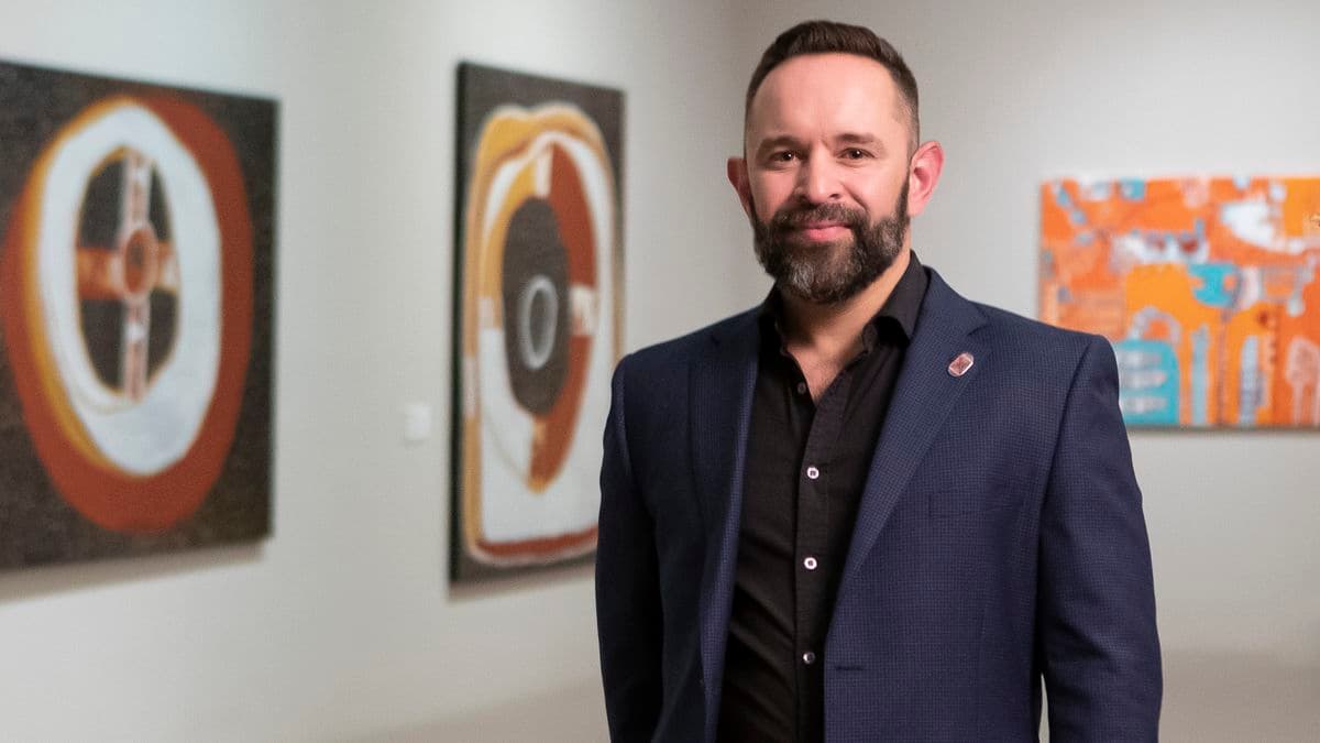 Portrait of a man standing in front of artworks in an Art Gallery