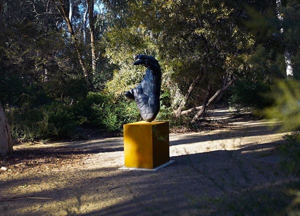 A black sculpture of an orangutan's foot on a yellow base