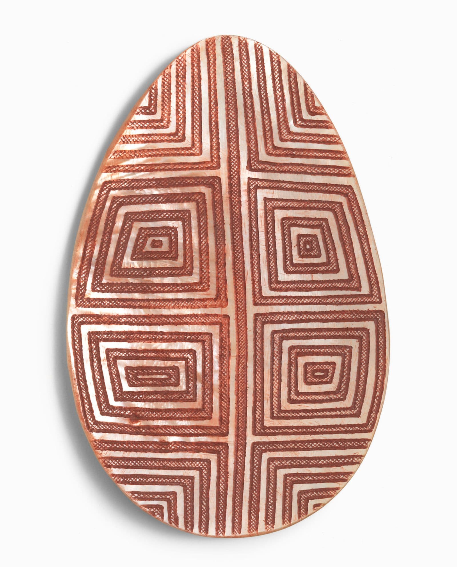 the inside of a large pearl shell that has been carved in an intricate design and coloured with reddish-brown ocher