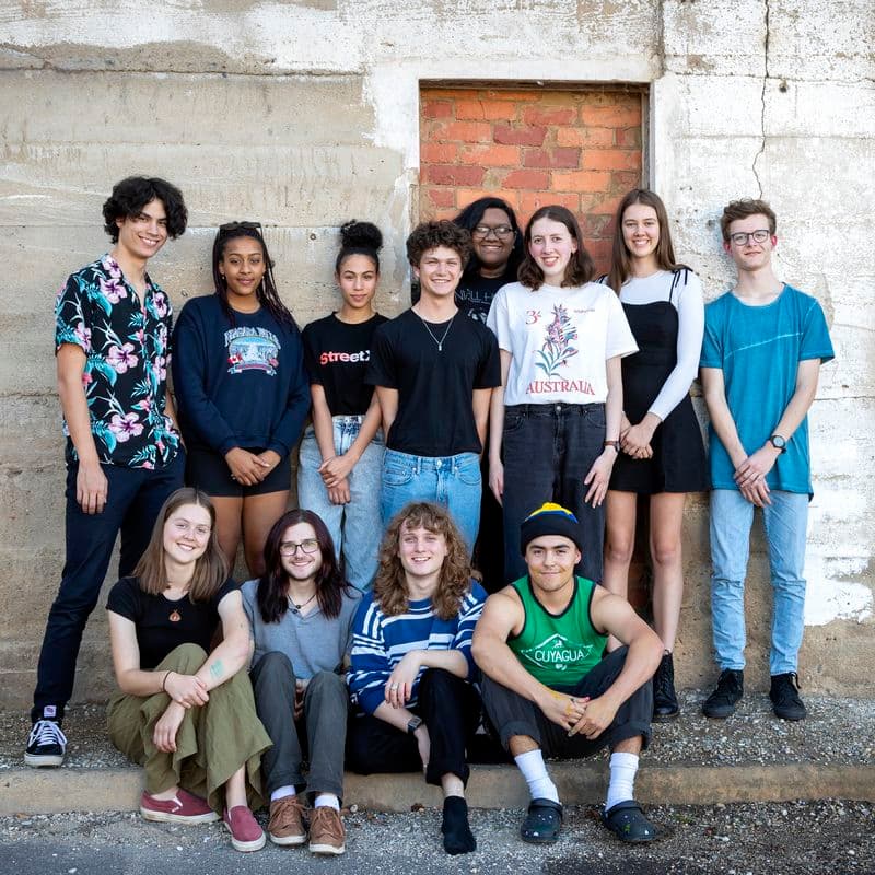 Group photo of teenagers standing and sitting against a wall