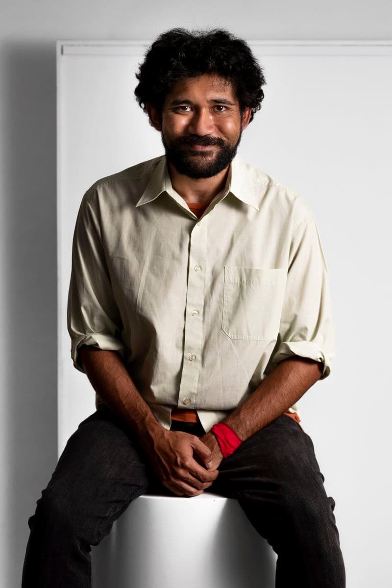 Photographic portrait of a man standing against a white background.
